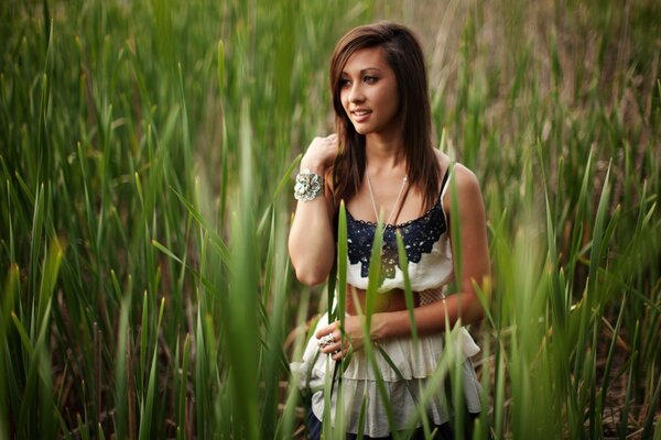 Fille réfléchie se promène parmi les hautes herbes