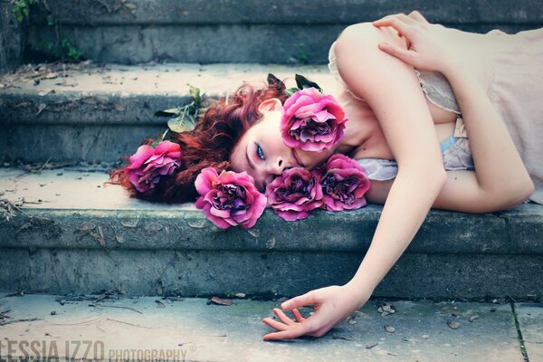 Beautiful girl in flowers on the stairs