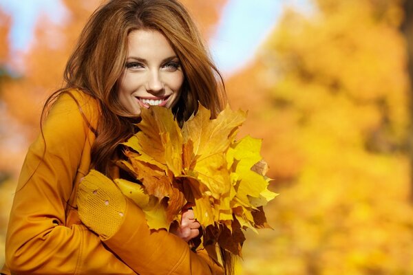 A girl with a bouquet of yellow leaves