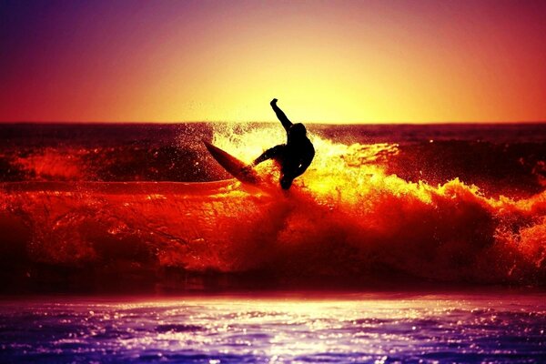 Surfer auf dem Kamm einer Sonnenuntergangswelle