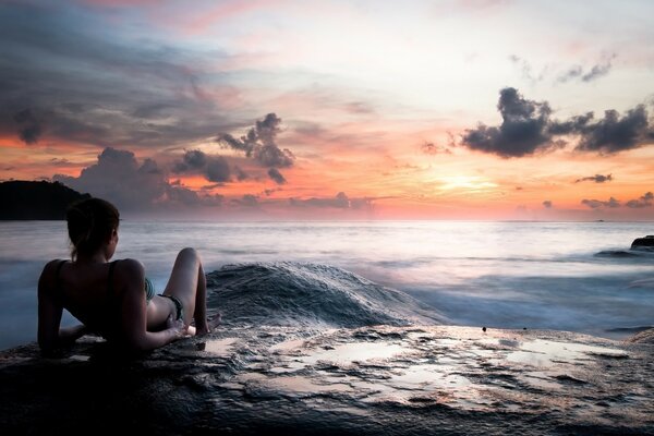 Mädchen am Meer schaut auf den Sonnenuntergang