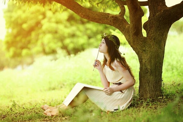 A girl in the garden under a tree is writing a memoir