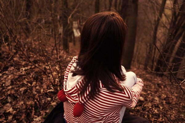 A girl is sitting on fallen leaves