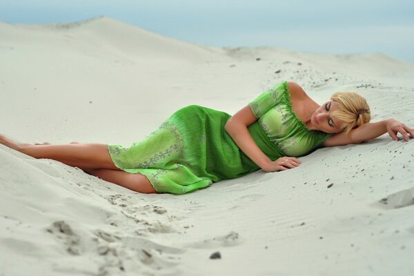 A girl in a green dress on the sand