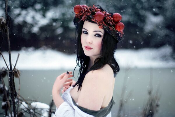 Hermosa chica con una corona roja en la cabeza en invierno