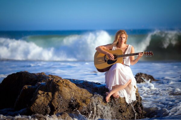 Chica con guitarra en la orilla del mar