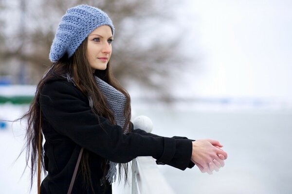 A girl stands on a bridge in winter