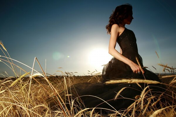 A girl in a field at sunset among the ears