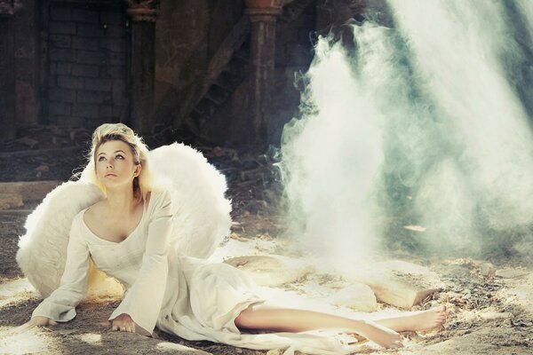 A girl with a white dress with white wings on the ground