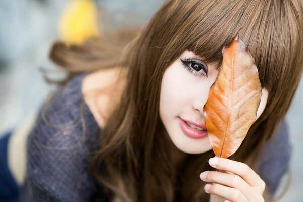 A girl with long hair with a leaf in her hand