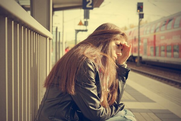 The girl on the platform is waiting for the train. Long hair