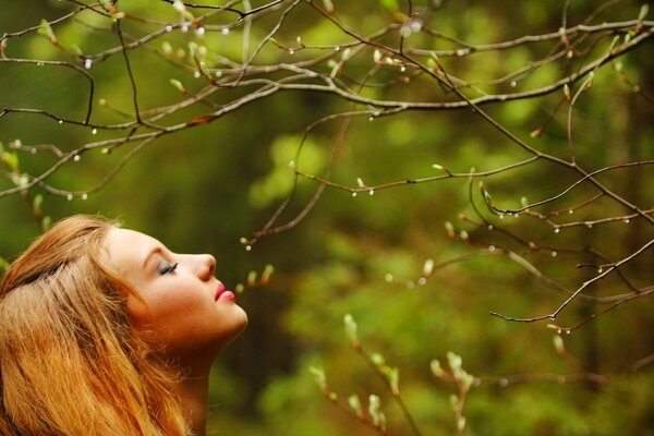 A girl sniffs the buds of trees