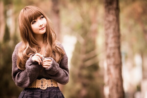 Oriental girl with long hair on a blurry background of trees