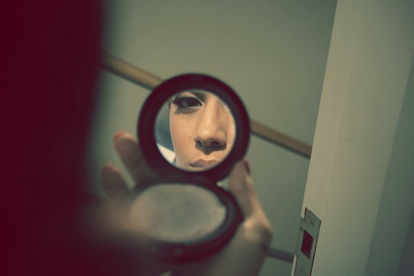 Photo of a woman s reflection in a pocket mirror