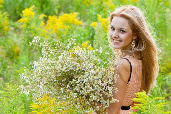 Smiling girl with a bouquet of wild flowers