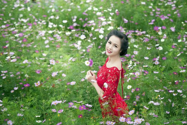 Fille en robe rouge se tient en fleurs