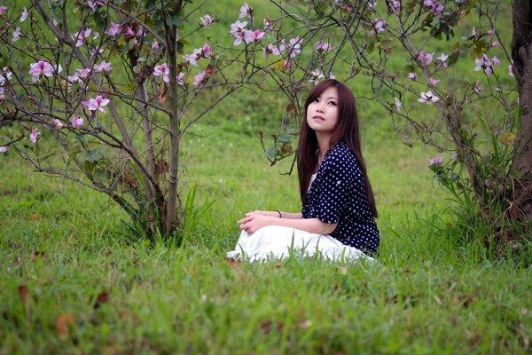 A girl is sitting on the grass in the park