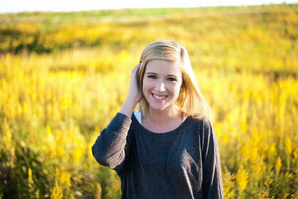 Süße Blondine im Feld mit Blumen