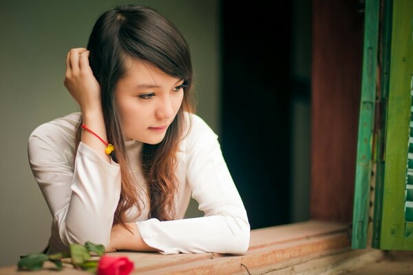 Sad girl in a room with a rose