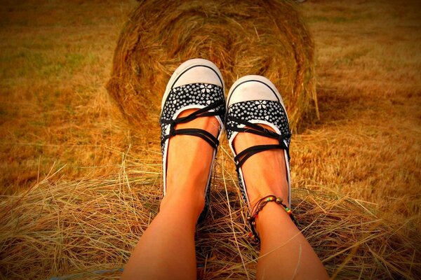 Women s legs on the background of a haystack