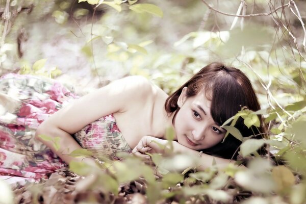 A girl through the green leaves of trees