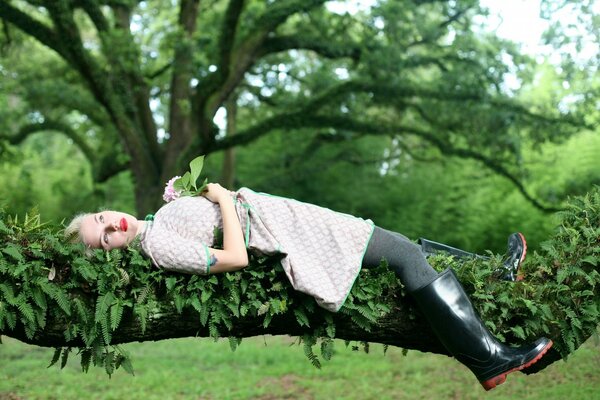 Ragazza sdraiata su un ramo di albero verde