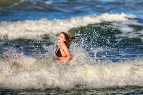 Chica en traje de baño corriendo por las olas