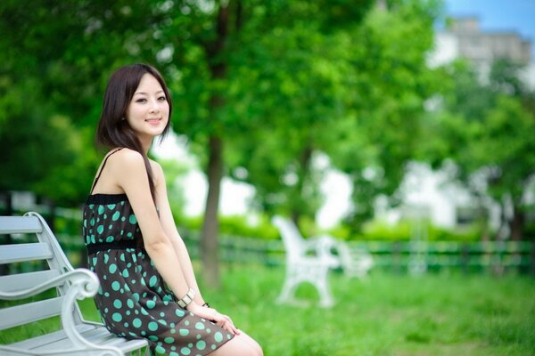 Fille en robe d été sur le banc dans le parc