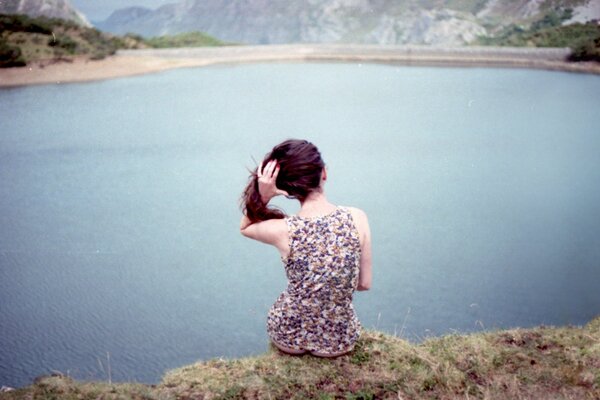 A girl is sitting on the shore of the lake