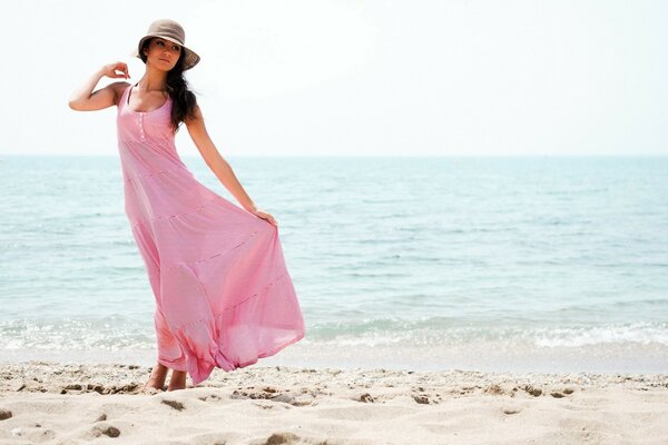 A girl in a pink dress walks along the seashore