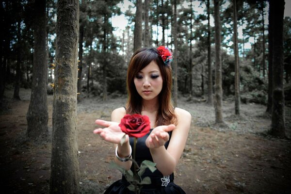 A girl in the forest enchants a rose