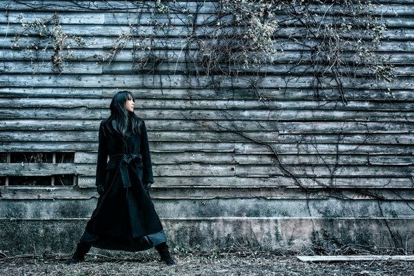 A girl in a raincoat on the background of an old barn