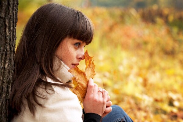 Una niña sostiene hojas de otoño en sus manos