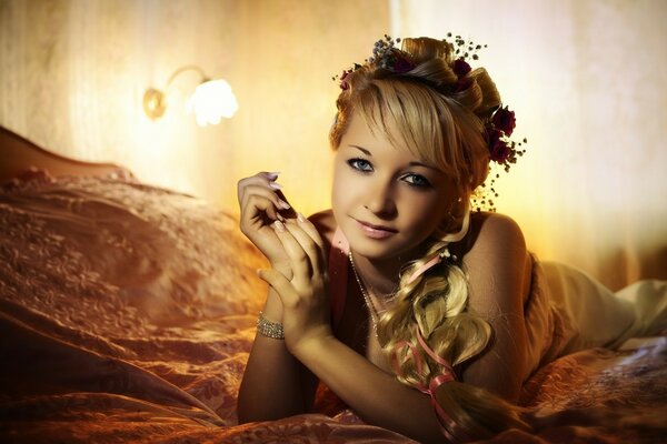 A girl on the bed with a braided braid and a wreath on her head