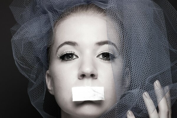 Portrait of a girl with a taped mouth and a veil