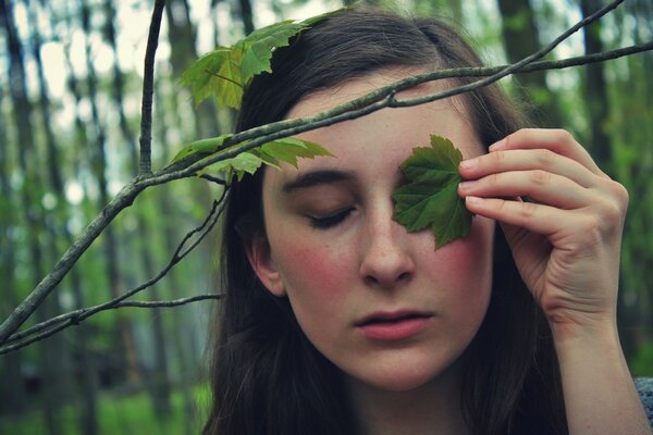 The girl covered her eye with a leaf