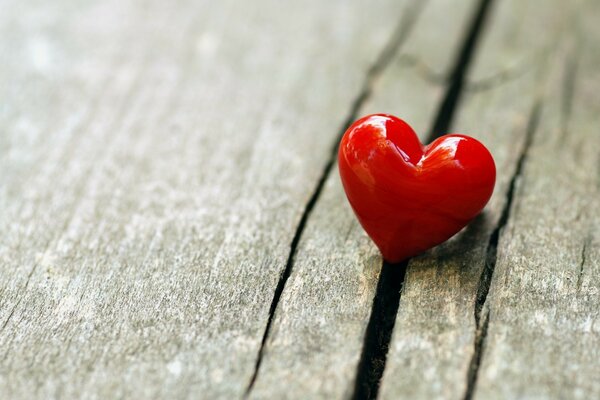 A red heart stuck in a crack in the wooden surface