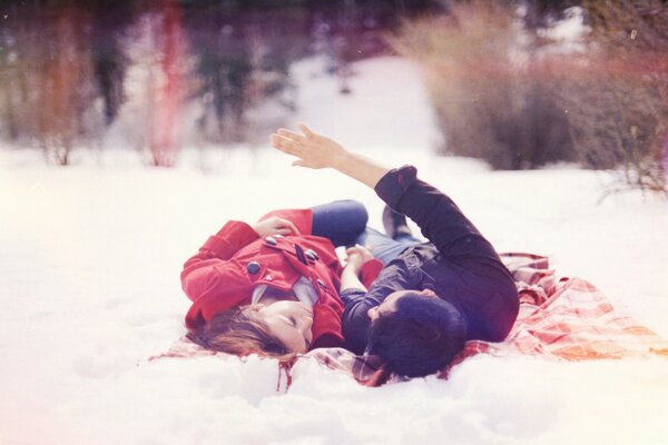 A girl with a guy lying in the snow