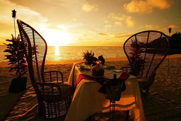 Tisch und Stühle auf Strand und Sonnenuntergang Hintergrund