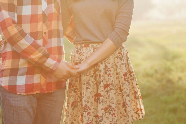 Pareja se toma de la mano en una sesión de fotos en el campo