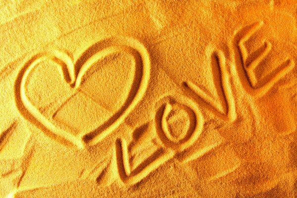 The word love and a heart in the sand