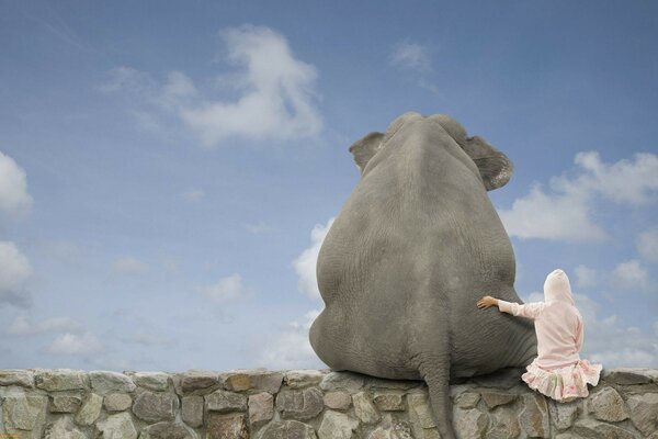 Una niña abrazada con un elefante contra el cielo