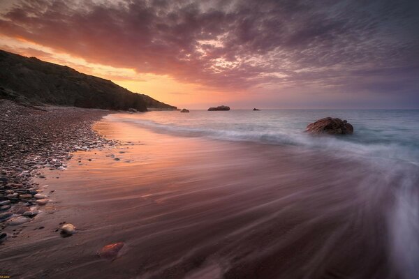 The receding wave against the background of the sunset sky