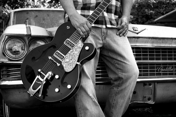 A man with a guitar near the car