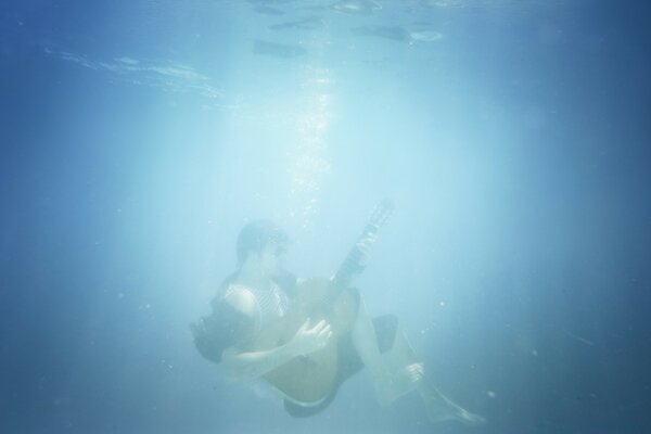 Imagen de un músico con una guitarra bajo el agua