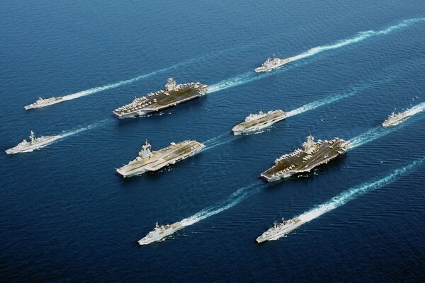 Aircraft carriers escorted by small military vessels