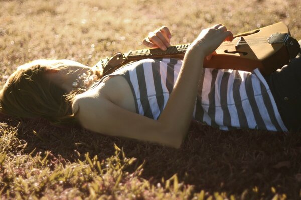 Adult girl on the grass with a guitar