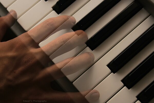 Mano che suona i tasti del pianoforte in bianco e nero