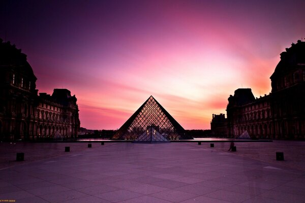 Paris teki ünlü Louvre Müzesi, turist kalabalığı olmayan pembe bir gün batımının ortasında