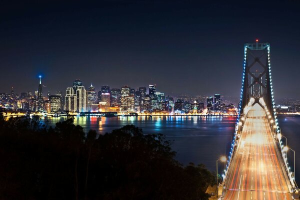 Une ville étincelante de toutes les couleurs à l horizon, un pont grandiose au premier plan